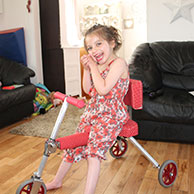 Summer sitting on her custom made folding trike with back support