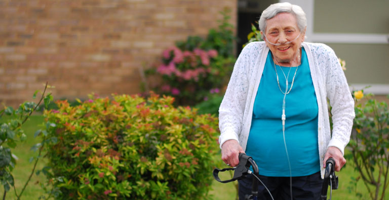 An older lady uses her specially adapted walking frame from DEMAND
